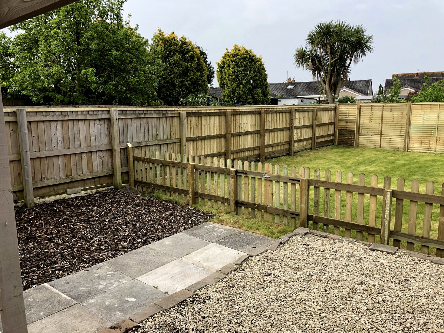 Low-maintenance gravel garden with fencing, paving and retained tree