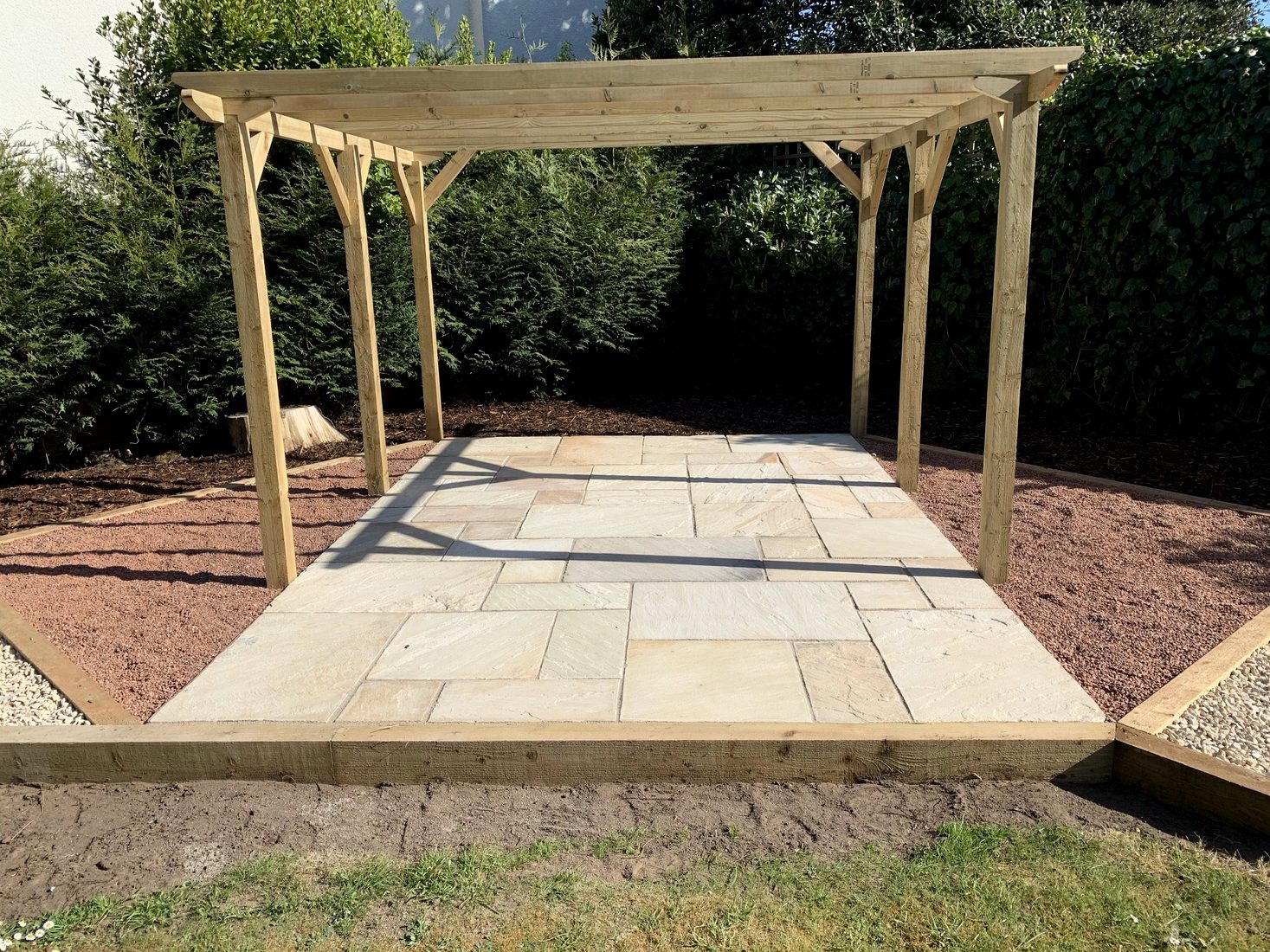 Natural stone patio and timber pergola in a landscaped garden